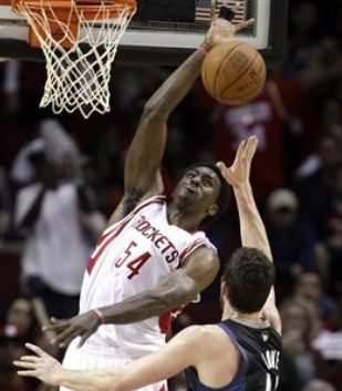 Houston Rockets' Patrick Patterson (54) goes up to block the shot of Minnesota Timberwolves' Kevin Love (42) as Rockets' Kyle Lowry, left, falls to the floor during the fourth quarter of an NBA basketball game on Friday, Feb. 17, 2012, in Houston. The Timberwolves defeated the Rockets 111-98. (AP Photo/David J. Phillip)